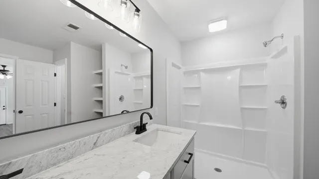a bathroom with a granite countertop sink a mirror and shower