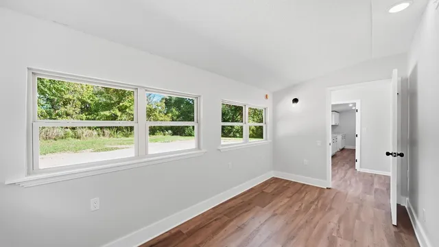 a view of an empty room with wooden floor and a window