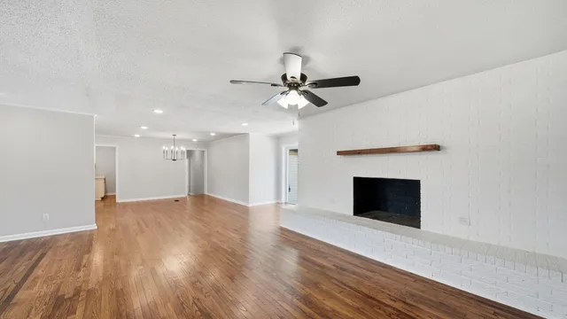 a view of an empty room with wooden floor fireplace and a window