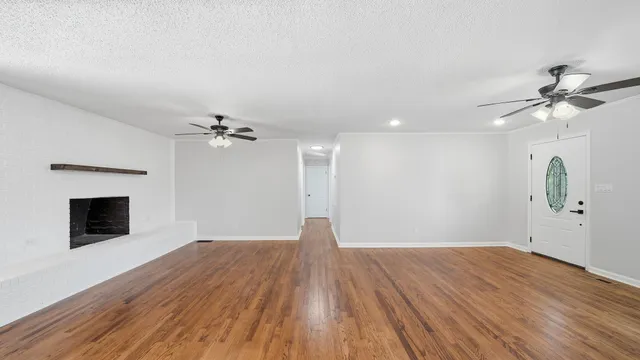 a view of empty room with wooden floor and ceiling fan