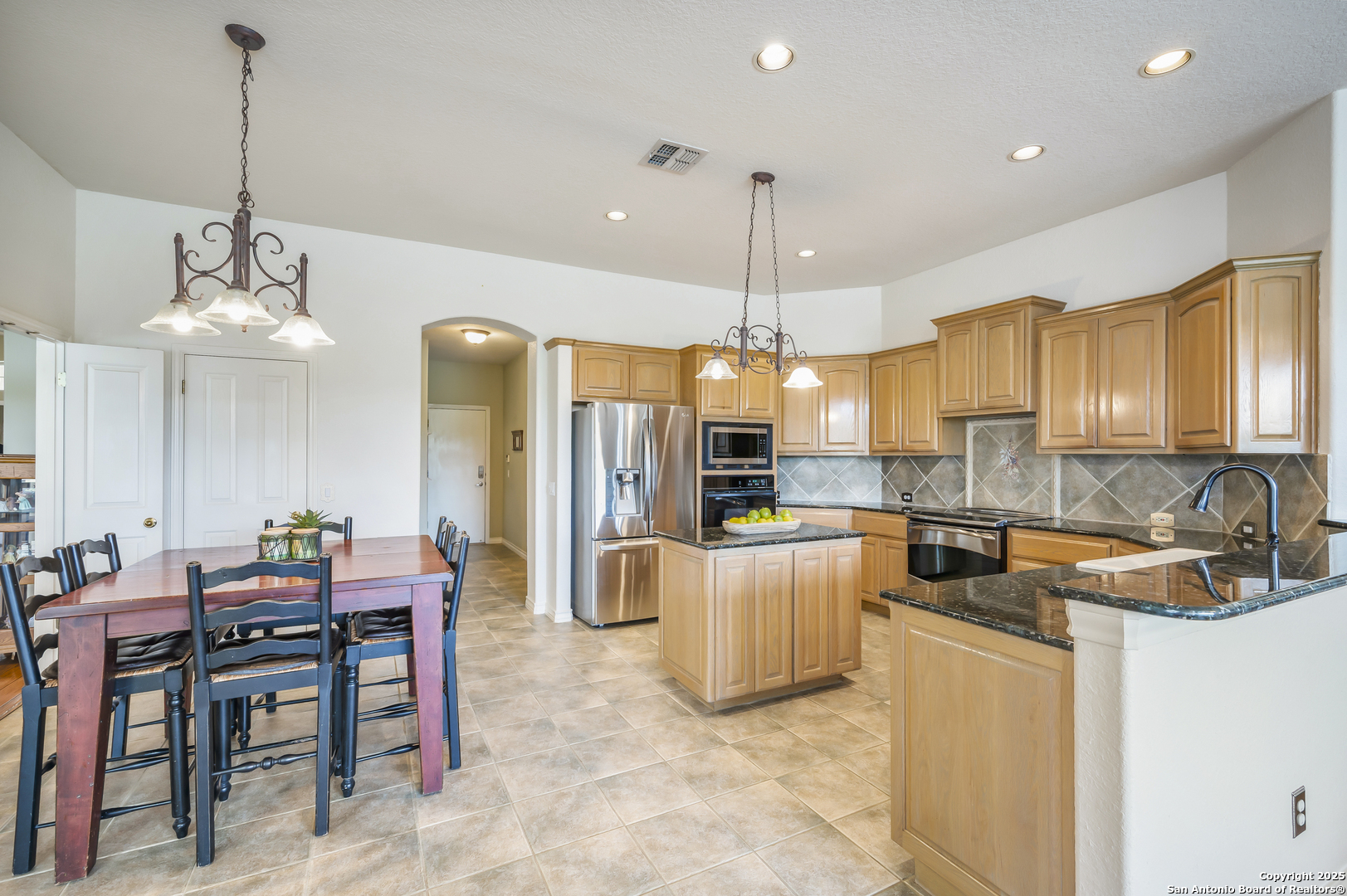 221 Park Ridge Boerne, TX 78006 - Photo 13 of 35 a kitchen with stainless steel appliances kitchen island granite countertop a table chairs and a refrigerator