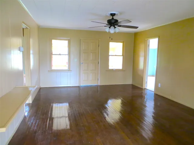 a view of an empty room with window and wooden floor