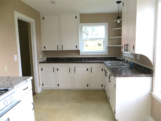 a kitchen with granite countertop a sink a stove and cabinets