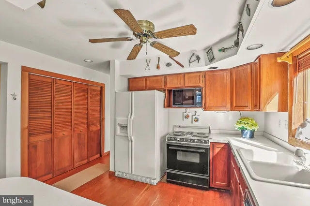 a kitchen with stainless steel appliances granite countertop a refrigerator a stove and a sink with wooden floor