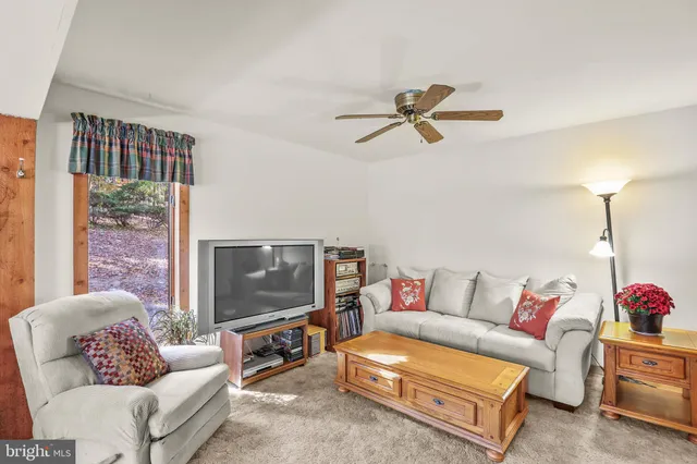 a living room with furniture a ceiling fan and a window