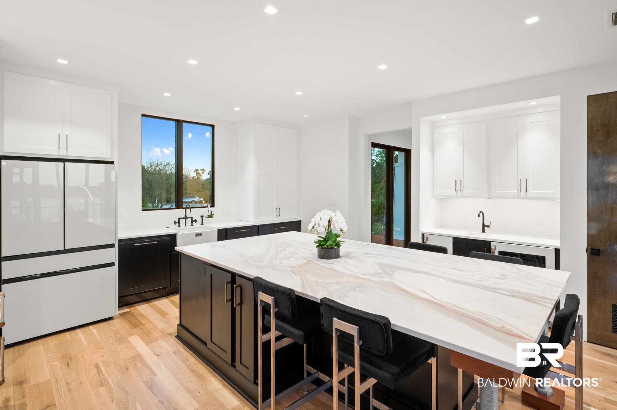 33349 River Road Orange Beach, AL 36561 - Photo 11 of 61 Gourmet kitchen featuring a large central island with a stone countertop, light wood-finish flooring, white upper cabinetry, and dark lower cabinetry