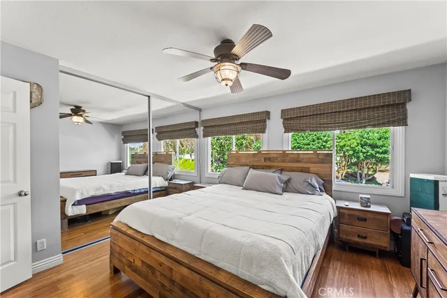 a bedroom with a bed and a large window with wooden floor