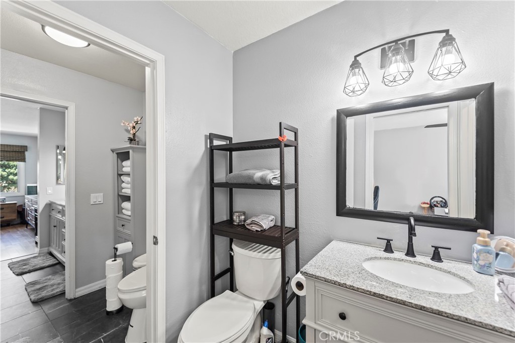 23653 Lexington Court, Unit 2 Laguna Niguel, CA 92677 - Photo 25 of 30 a bathroom with a granite countertop toilet a sink and a mirror