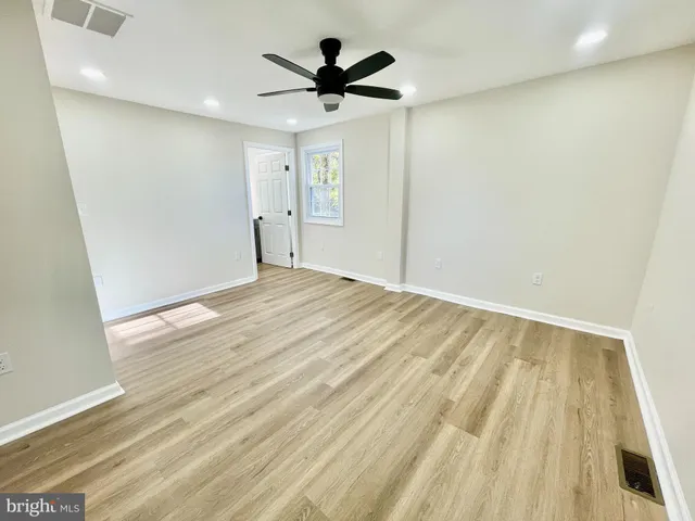 an empty room with wooden floor and ceiling fan