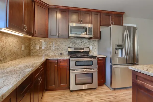 a kitchen with granite countertop wooden cabinets and stainless steel appliances
