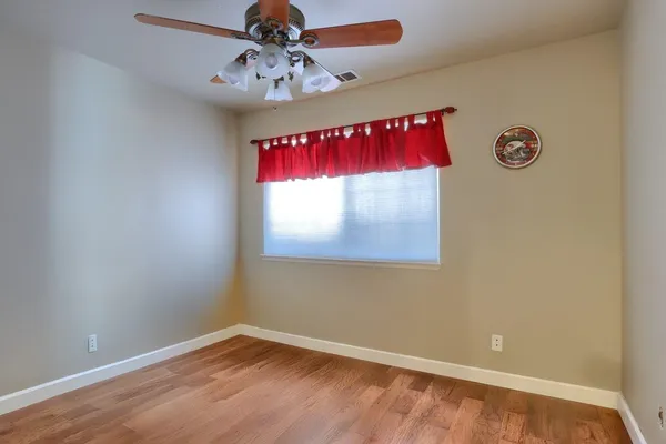 an empty room with windows and fan