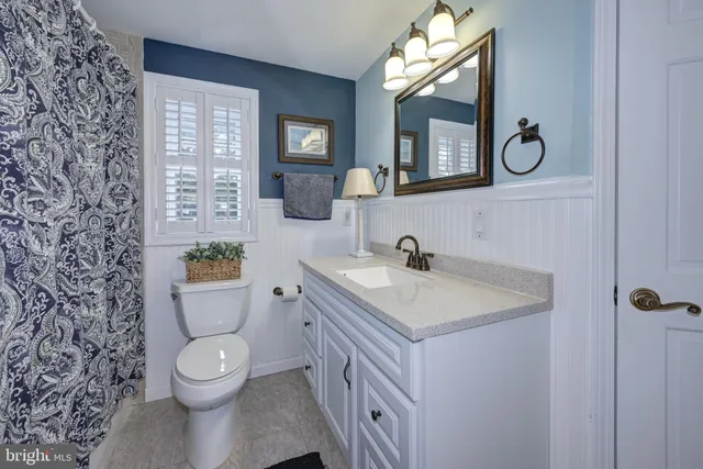 a bathroom with a toilet sink vanity and mirror
