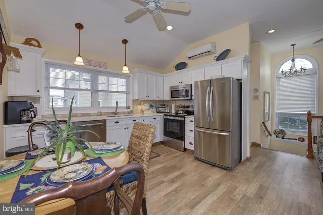 a kitchen with stainless steel appliances granite countertop a refrigerator a sink dishwasher a dining table and chairs with wooden floor