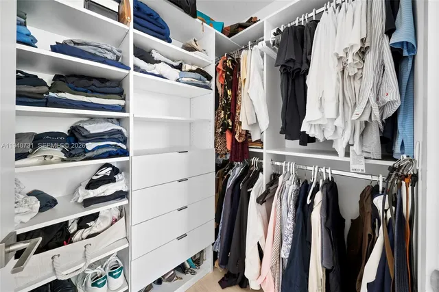 a view of walk in closet with clothes and shoes