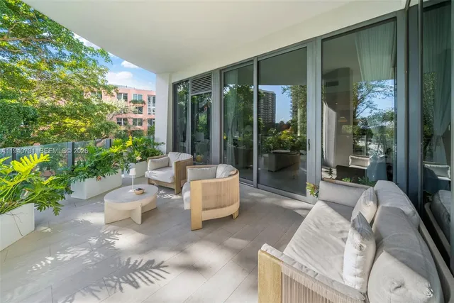 a living room with patio furniture and a potted plant