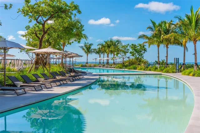 a view of a swimming pool with a garden and palm trees