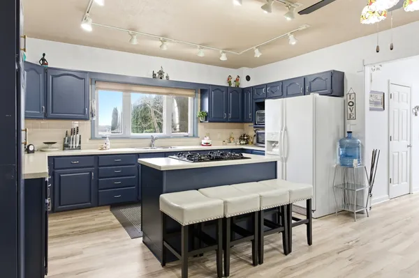 a kitchen with stainless steel appliances granite countertop a stove a refrigerator a sink dishwasher a dining table and chairs with wooden floor