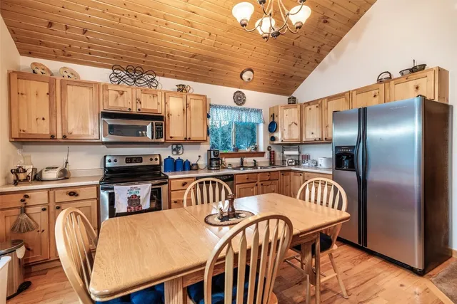 a kitchen with stainless steel appliances granite countertop a dining table chairs refrigerator and microwave