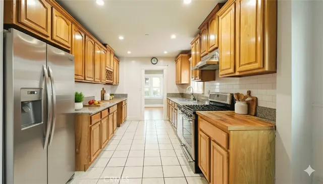 a kitchen with stainless steel appliances granite countertop a refrigerator a stove and a sink