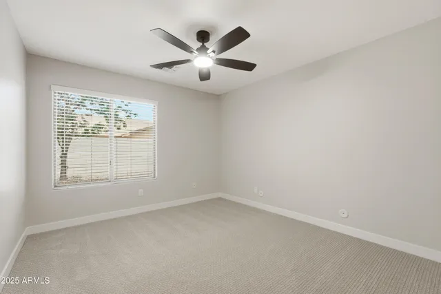 an empty room with windows and fan