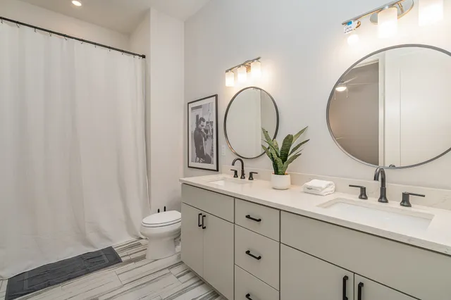 a bathroom with a double vanity sink mirror and toilet