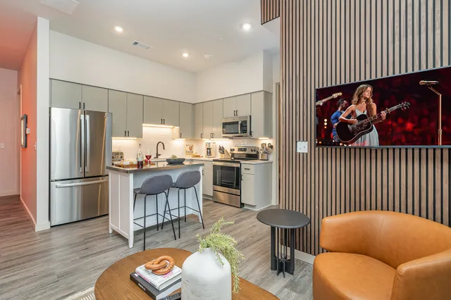 a living room with stainless steel appliances furniture and a wooden floor