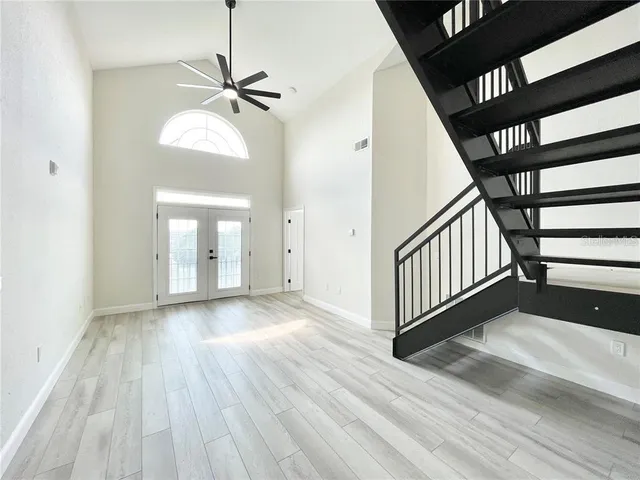 a view of an empty room with wooden floor and a ceiling fan
