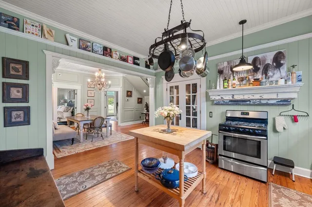 a kitchen with stainless steel appliances kitchen island granite countertop a table chairs in it and wooden floors