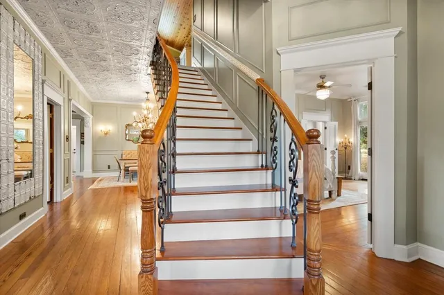 a dining room with wooden floor a chandelier a wooden table and chairs