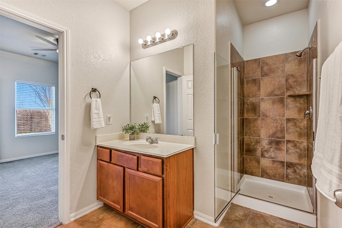 4206 Brightridge Court Rosenberg, TX 77471 - Photo 16 of 27 This first floor Jack & Jill style bathroom offers a single cultured marble vanity, stained wood cabinetry, Hollywood lighting, and a tiled walk-in shower with a glass enclosure.