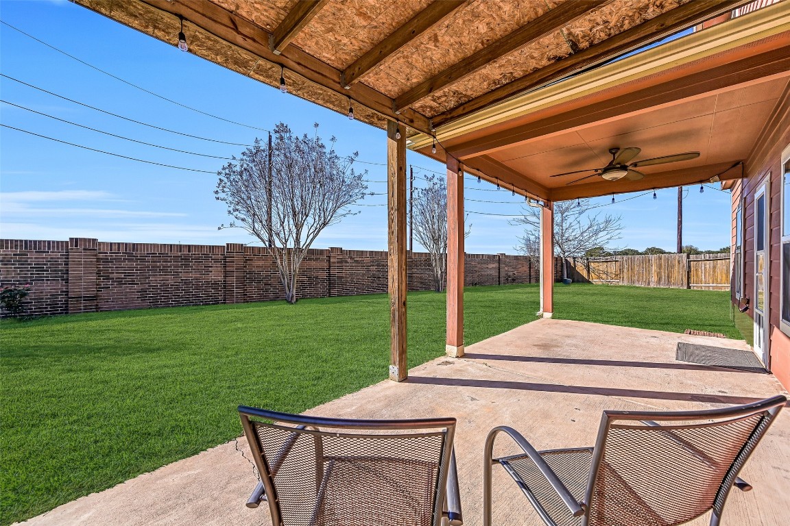 4206 Brightridge Court Rosenberg, TX 77471 - Photo 25 of 27 Exit through the back door from the family room wot relax on this covered back patio with a ceiling fan and string lighting ambiance, overlooking a large yard tht's perfect for outdoor relaxation and entertaining.