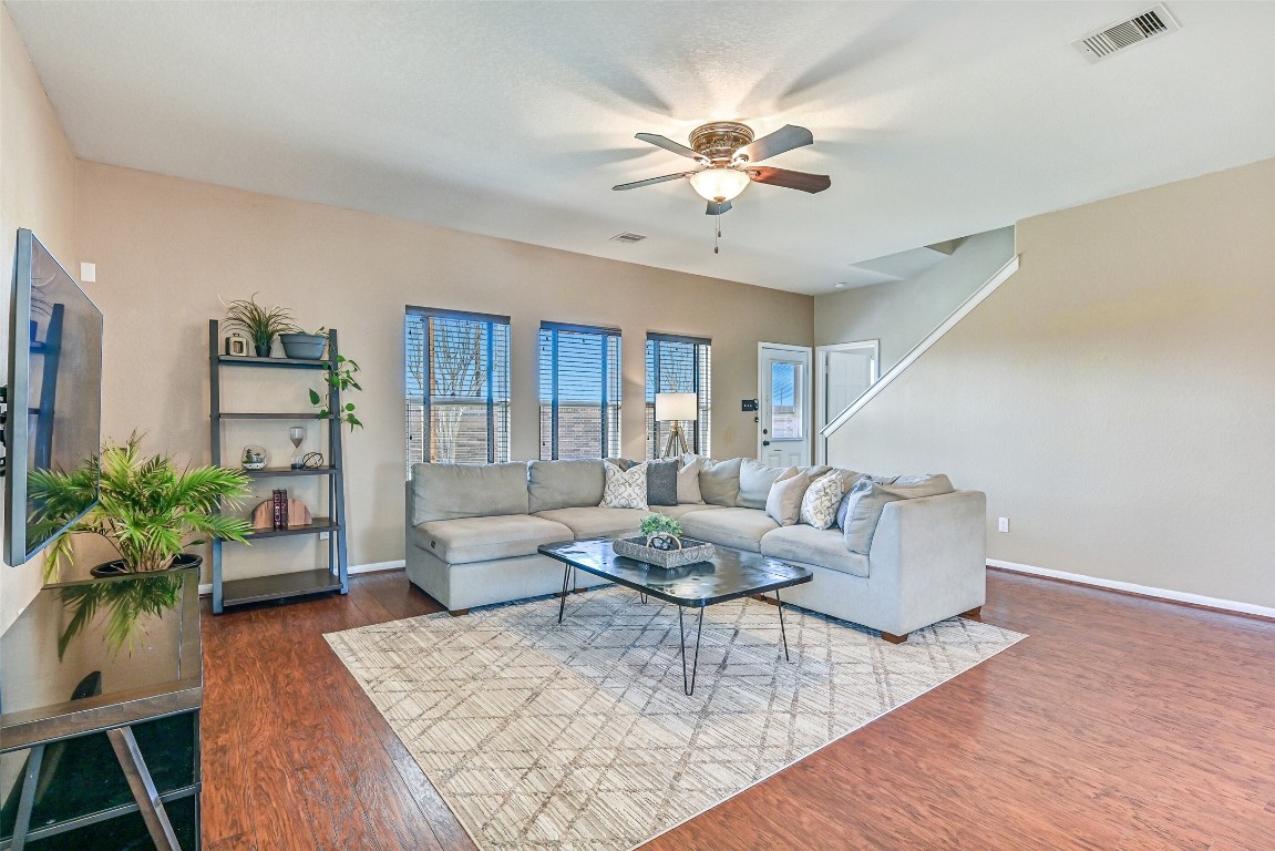 4206 Brightridge Court Rosenberg, TX 77471 - Photo 5 of 27 Gather in this spacious living room with wood-look laminate flooring, neutral paint tones, a lighted ceiling fan, and multiple double paned windows that flood the space with natural light.