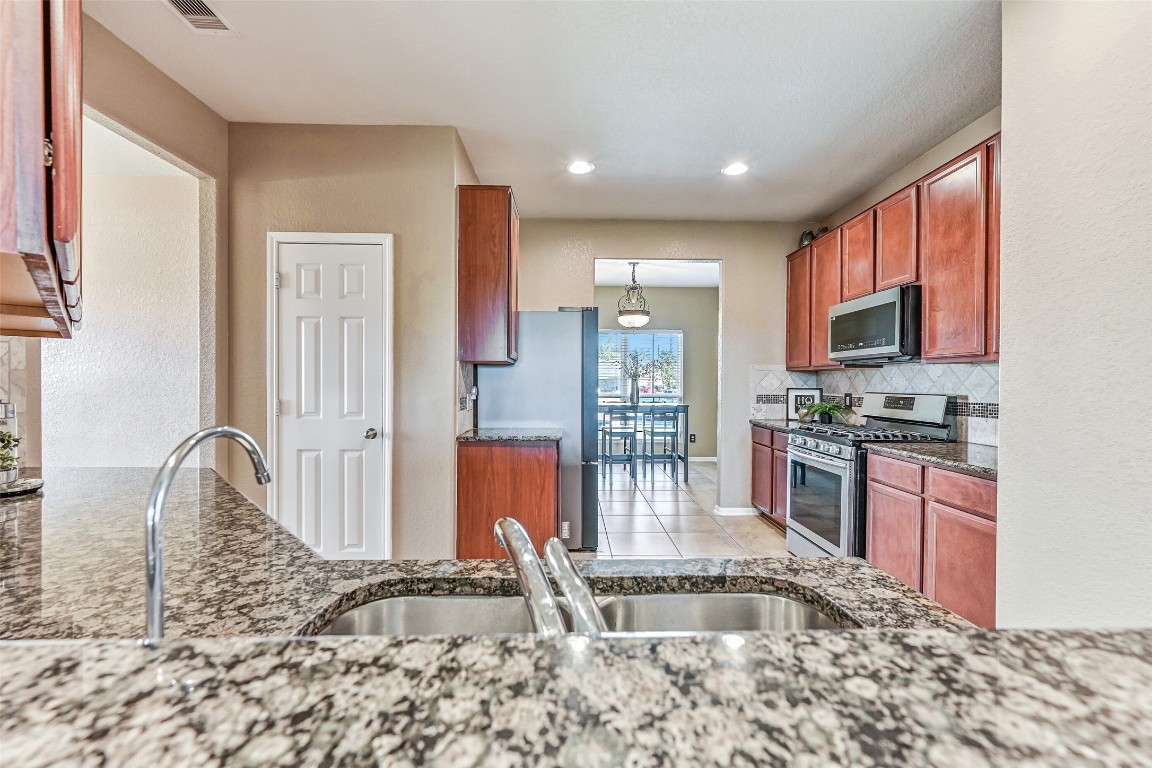 4206 Brightridge Court Rosenberg, TX 77471 - Photo 10 of 27 This view, from the raised breakfast bar in the kitchen, highlights the granite countertops, diagonally laid tile backsplash, recessed lighting, roomy pantry, ample workspace, and clear sightlines into the breakfast area.