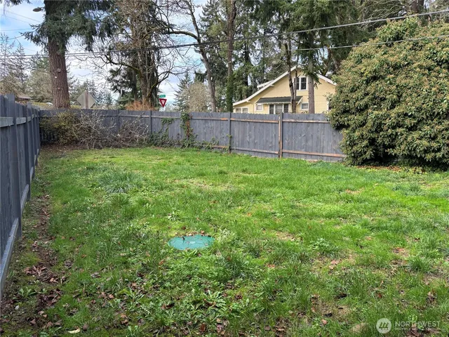 a view of a backyard with large trees and wooden fence