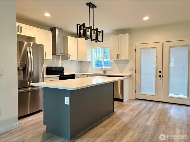 a kitchen with stainless steel appliances granite countertop a refrigerator a sink dishwasher a stove and a refrigerator