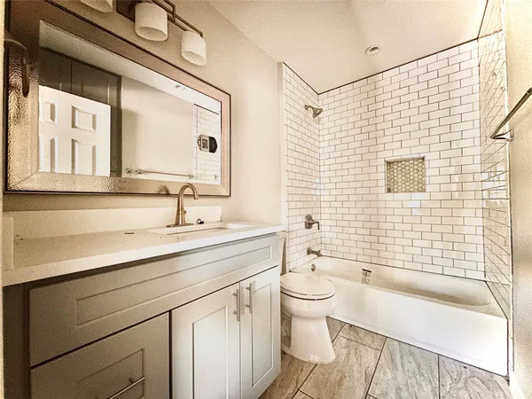 a bathroom with a sink a toilet a mirror a vanity and bathtub