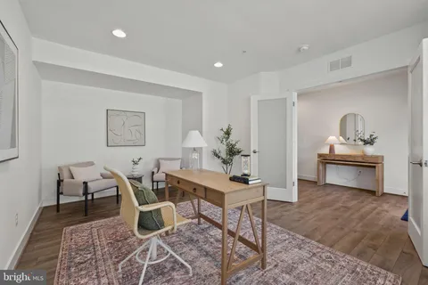 a kitchen with kitchen island a dining table chairs stainless steel appliances and wooden floor