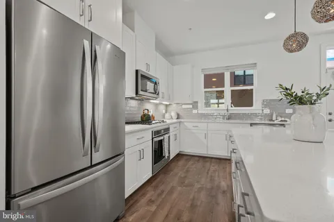 a large kitchen with kitchen island a dining table chairs and a wooden floor
