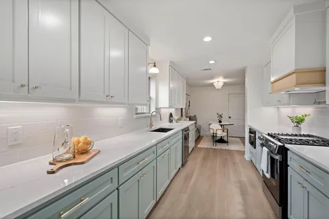 a kitchen with stainless steel appliances sink stove and cabinets