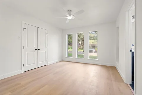 a view of an empty room with a window and wooden floor