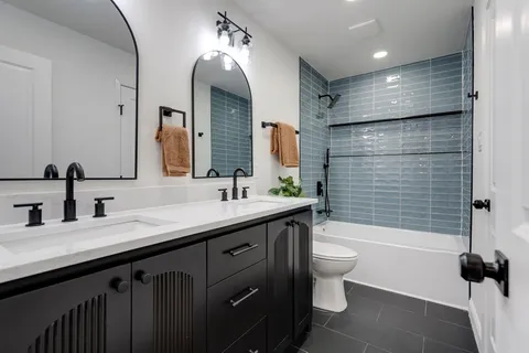 a bathroom with a double vanity sink toilet and shower