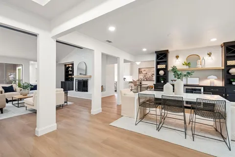 a living room with furniture a wooden floor and next to kitchen view