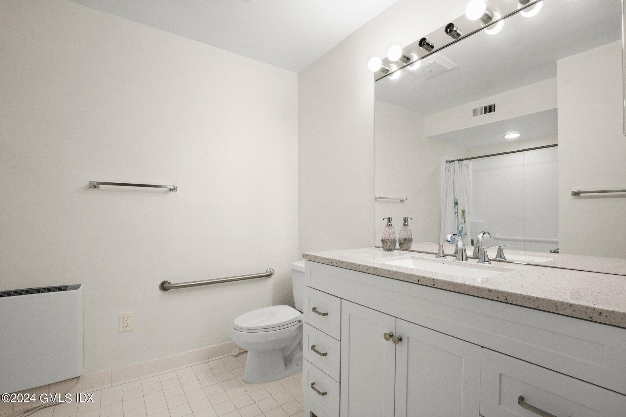 351 Pemberwick Road, Unit 109 Greenwich, CT 06831 - Photo 8 of 9 a bathroom with a granite countertop sink a toilet and a mirror