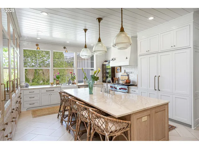 a kitchen with kitchen island granite countertop a stove a sink a center island and a window