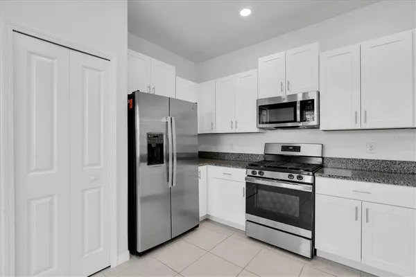 a kitchen with stainless steel appliances white cabinets white stove a microwave and a refrigerator