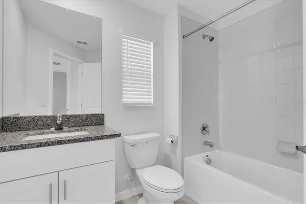 a bathroom with a granite countertop toilet a sink and a bathtub