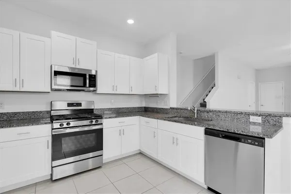 a kitchen with granite countertop white cabinets white stainless steel appliances and a sink