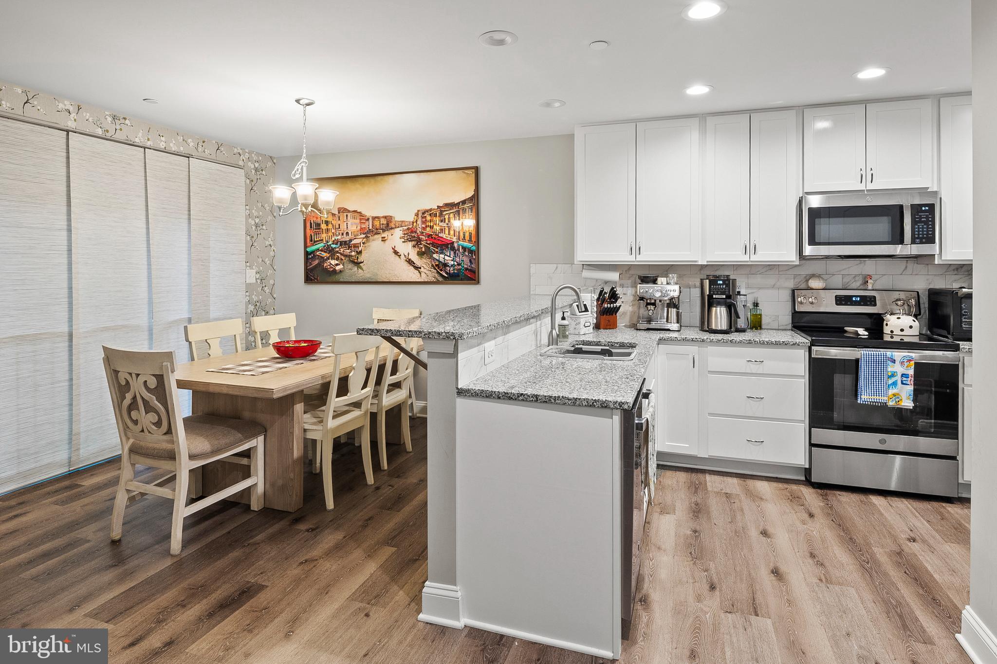 898 Marigold Road Glen Burnie, MD 21060 - Photo 8 of 33 a kitchen with stainless steel appliances granite countertop a stove top oven a refrigerator a dining table and chairs with wooden floor