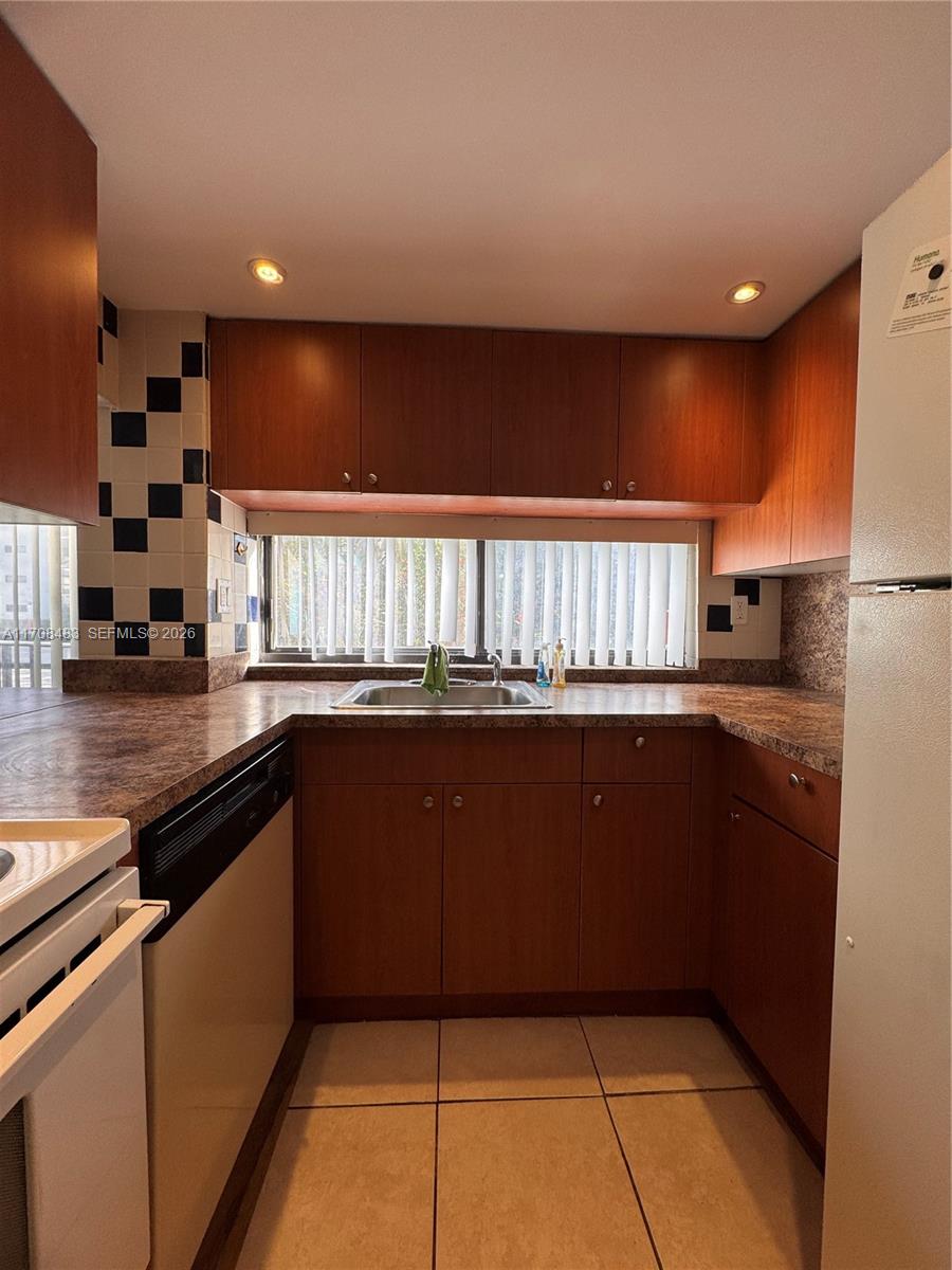 16919 North Bay Road, Unit 117 Sunny Isles Beach, FL 33160 - Photo 8 of 20 a kitchen with kitchen island granite countertop a refrigerator and a counter top space