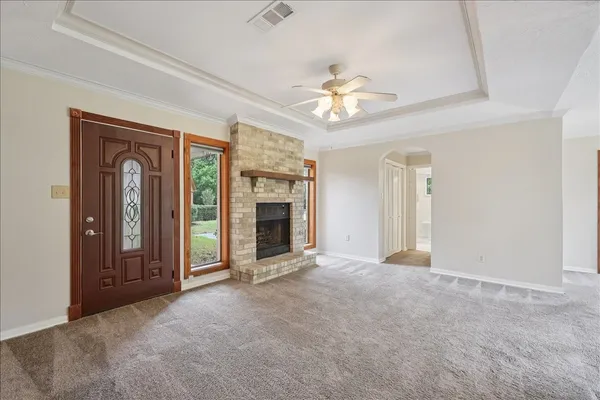 an empty room with windows fireplace and a ceiling fan